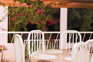 a table with white chairs and pink flowers at Pousada do Ribeirão in Andrelândia