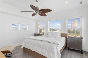 a white bedroom with a large bed and windows at Guest House Topsail in Topsail Beach