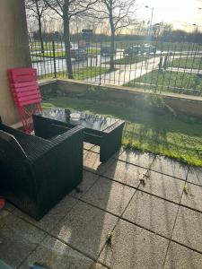 a patio with a table and a bench and a red chair at cosy appartement Disneyland Paris val d'Europe la vallée Village parking inclus 650m de la gare RER in Montévrain