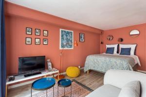 a bedroom with orange walls and a bed and a tv at Sainte Hélène - Location studio - Lyon 2 in Lyon
