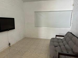 a living room with a couch and a flat screen tv at Casa estrella del bosque in Coajomulco