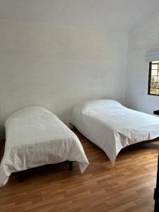 Cet hébergement comprend 2 lits dans une chambre dotée de murs blancs et de parquet. dans l'établissement Casa estrella del bosque, à Coajomulco