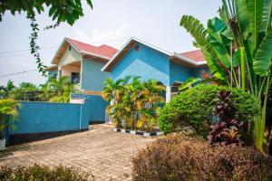 una casa azul con muchos árboles y plantas en PEACE Homes, en Kigali