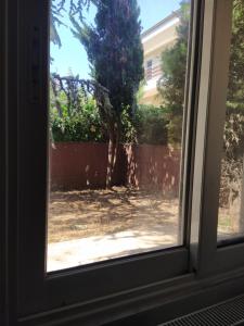 a window with a view of a tree in a yard at 3 STEPS in Alexandroupoli