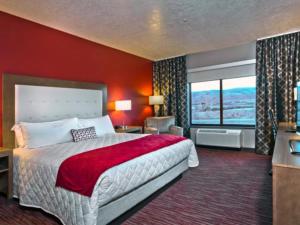 um quarto com uma cama grande e uma parede vermelha em Shoshone Rose Casino & Hotel em Lander