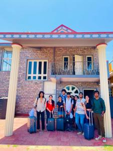 a group of people standing in front of a house with luggage at COORG STONE VILLA in Madikeri
