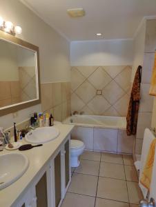 a bathroom with two sinks and a tub and a toilet at Queen Angel Suite. Stunning Apartment on Grafton Beach with Direct Beach Access in Black Rock