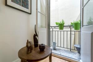 a room with a table and a balcony with plants at République - meublé calme sur la presqu'île in Lyon