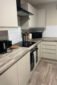 La cuisine est équipée de placards blancs et d'un four avec plaques de cuisson. dans l'établissement Comfortable & Spacious Apartment, à Stoke-on-Trent