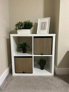 a white book shelf with potted plants on it at Comfortable & Spacious Apartment in Stoke on Trent