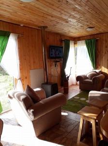 Sala de estar con 2 sofás y TV en Cabañas Amanecer, en Riñinahue