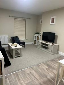 uma sala de estar com uma televisão de ecrã plano e um sofá em Comfortable & Spacious Apartment em Stoke-on-Trent