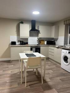 Il comprend une cuisine équipée d'une table, de chaises et d'une cuisinière. dans l'établissement Comfortable & Spacious Apartment, à Stoke-on-Trent
