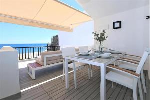 een witte tafel en stoelen op een balkon met uitzicht op de oceaan bij Beachhouse GALORE in Estepona
