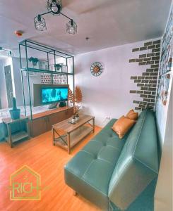 ein Wohnzimmer mit einem grünen Sofa und einem TV in der Unterkunft Cozy Condo in Marilao Bulacan - TRP10 in Marilao
