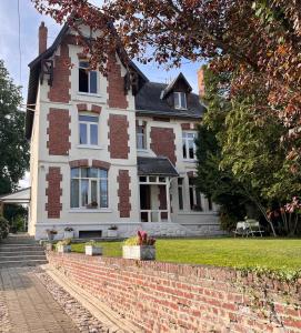 ein weißes Haus mit Ziegelwand in der Unterkunft Vers le soleil levant in Croisilles