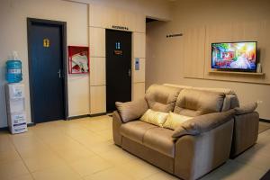 エンカルナシオンにあるHotel Rio Doradoのテレビ付きの客室で、茶色のソファが備わります。