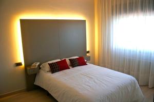 1 dormitorio con cama blanca y ventana grande en Apartamentos Angelito Playa América, en Nigrán