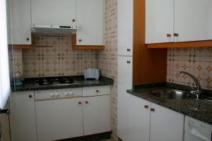 una pequeña cocina con armarios blancos y fregadero en Apartamentos Angelito Playa América, en Nigrán