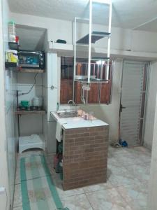a kitchen with a sink and a brick wall at Mini Casa em Arraial d'Ajuda in Porto Seguro
