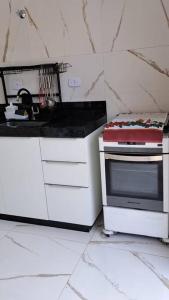 a white kitchen with a stove and a microwave at Casa na martim de Sa in Caraguatatuba