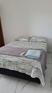 a bed with a blanket and a pillow on it at Casa na martim de Sa in Caraguatatuba
