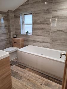 ein Badezimmer mit einer weißen Badewanne und einem WC in der Unterkunft Looe, Cornwall, Langunnett Cottage in Looe