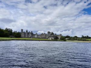 a castle sitting on the shore of a body of water at Whitethorn Lodge, Bed & Breakfast, Lackafinna in Cong