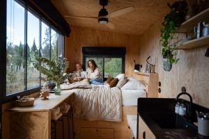 two people sitting on a bed in a tiny house at L'Atelier Tiny House Provence in Châteaurenard