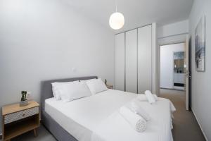 a white bedroom with a large white bed with two towels at Casa Lemonia 2 Min walking to BEACH in Kardamaina