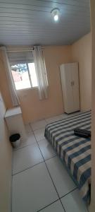 um pequeno quarto com uma cama e uma janela em Hospedagem e kitnetes D' Itália em Curitiba