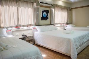 a bedroom with two beds and two windows at Hotel Rio Dorado in Encarnación