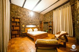 a bedroom with a bed and a chair in a room at Imbogo Diners and Lounge in Kisoro