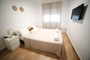 ein weißes Schlafzimmer mit einem Bett und einem TV in der Unterkunft Casa de playa, cerca de todo in Los Narejos