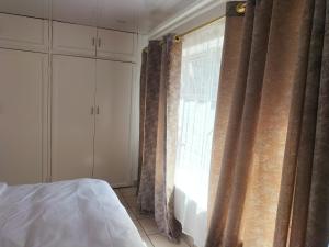The protea nest في جوهانسبرغ: غرفة نوم بسرير ونافذة مع ستائر