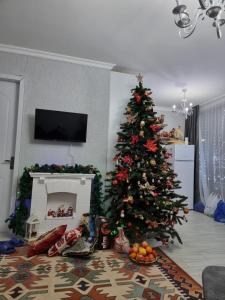 a christmas tree in a living room with a fireplace at Borjomi Plato house in Borjomi