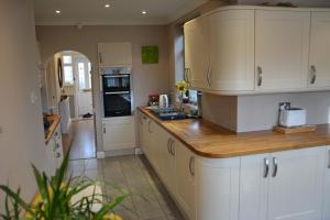 Cozy, modern, spacious 4 bedroom house in london في رومفورد: مطبخ بدولاب بيضاء وقمة كونتر