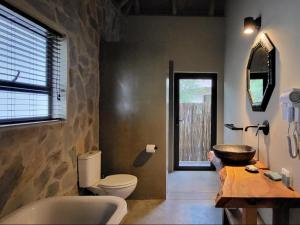 een badkamer met een toilet en een stenen muur bij Taaibos Bush Lodge in Hoedspruit