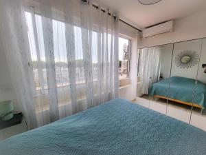 een slaapkamer met een blauw bed en een raam bij Appartement vue mer et port de plaisance ! in Fos-sur-Mer