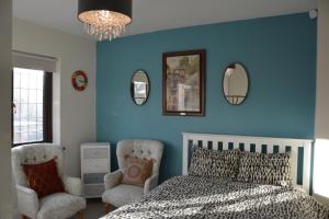 a bedroom with blue walls and a bed and two chairs at Cozy, modern, spacious 4 bedroom house in london in Romford