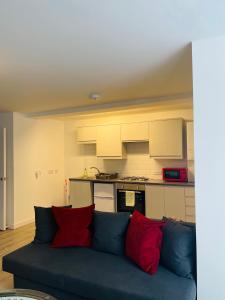 um sofá azul com almofadas vermelhas numa cozinha em One bedroom apartment, no 4 em Ilfracombe