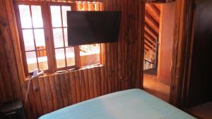 um quarto com uma cama, uma janela e uma televisão em Casa Rustica a pasos de la playa em El Quisco