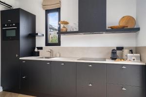 a kitchen with black cabinets and a sink at Bed and Breakfast Bij ons in het bos in Bergen op Zoom