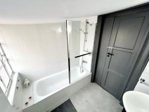 ein weißes Bad mit einer Badewanne und einer Dusche in der Unterkunft Low Cost Arroios Rooms in Lissabon