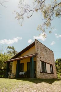 una pequeña casa amarilla con sillas delante en Villa Nova Holanda, en Mulungu