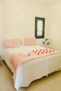 a white bed with red roses on top of it at Villa Nova Holanda in Guaramiranga
