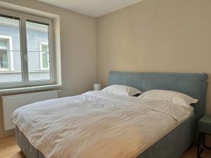1 dormitorio con 1 cama grande con sábanas blancas y ventana en City Apartment Sankt Pölten, en Sankt Pölten