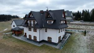 duży biały dom z czarnym dachem w obiekcie Willa u Bacy w Leśnicy
