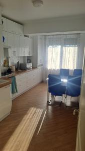 a kitchen with a table and blue chairs in it at Аэропорт Апартаменты Комфорт in Chişinău