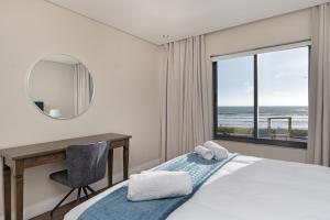 een slaapkamer met een bureau, een bed en een raam bij Eden on the Bay 167 by HostAgents in Bloubergstrand